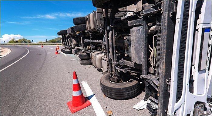 an overturned semi-truck on the side of a highway